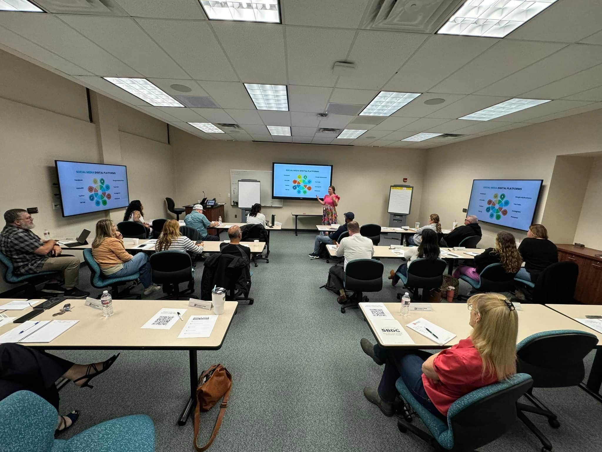 A classroom at Brazosport College Small Business Development Center. Margarey Valdez of MDT is presenting near a screen displaying 