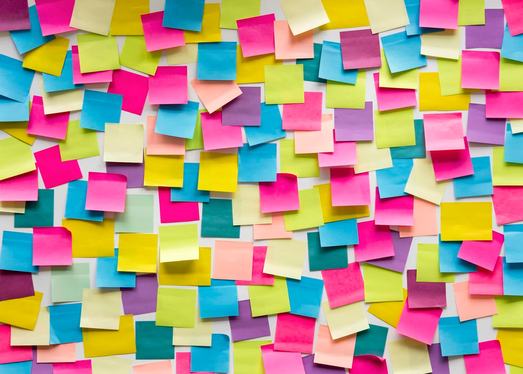 A large assortment of colorful sticky notes, are randomly arranged on a surface for small business planning. - Market Design Team: Define. Structure. Expand.