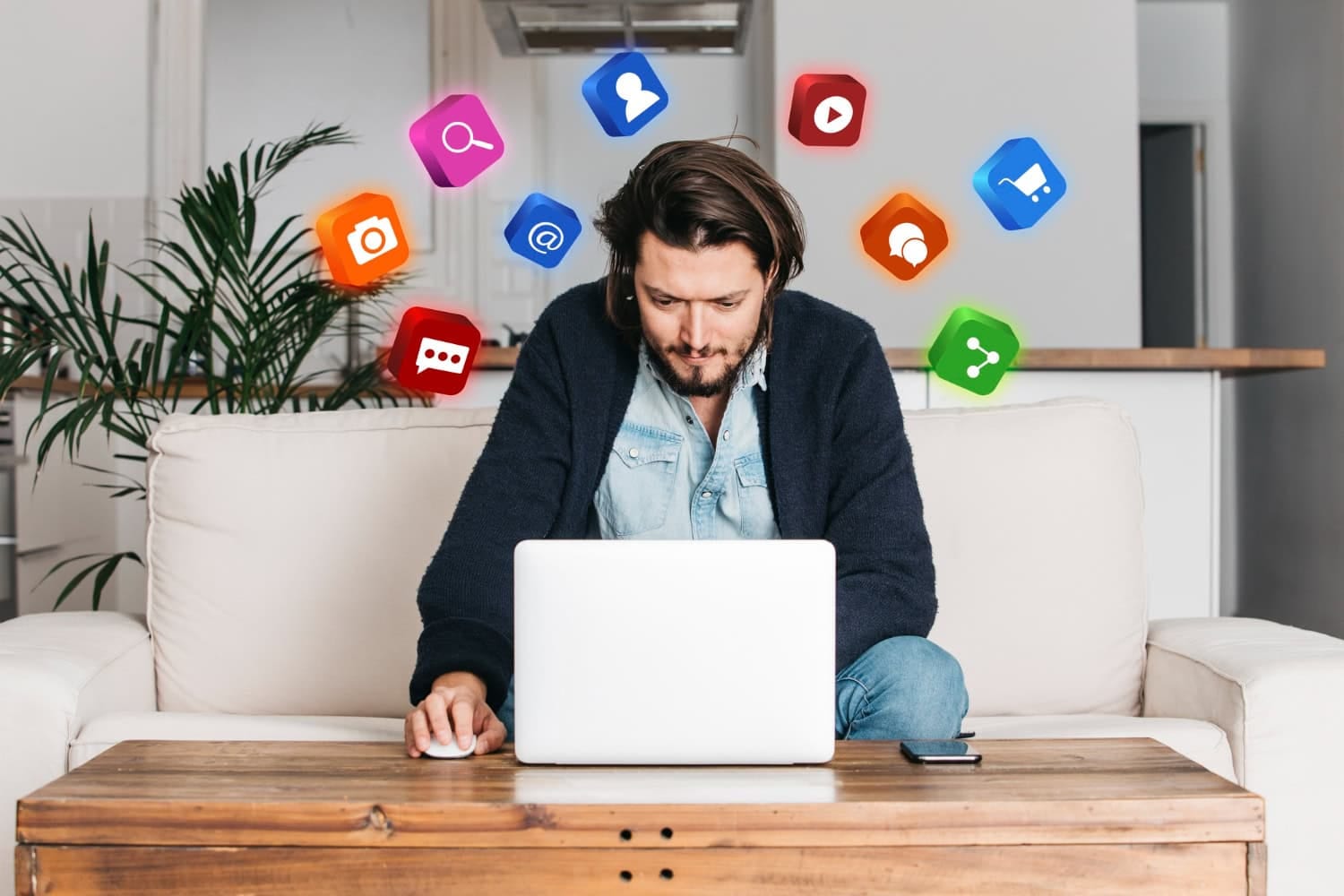 A man sits on a sofa in a bright Lake Jackson living room, using a laptop on a wooden table, with colorful social media and app icons digitally illustrated above his head. - Market Design Team: Define. Structure. Expand.