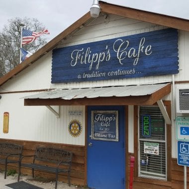 A small, single-story cafe with a blue sign reading 
