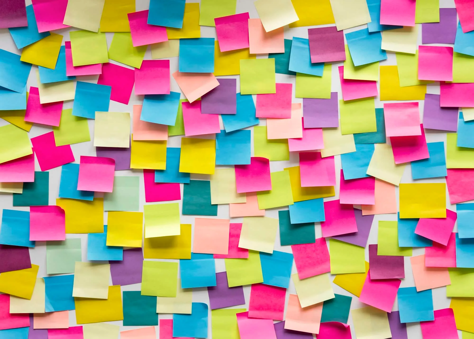 A large assortment of colorful sticky notes, are randomly arranged on a surface for small business planning. - Market Design Team: Define. Structure. Expand.